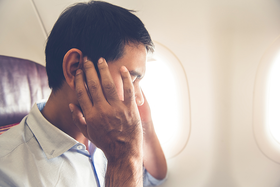 You can ease ear pain while flying by chewing gum or using pressure-relieving earplugs.