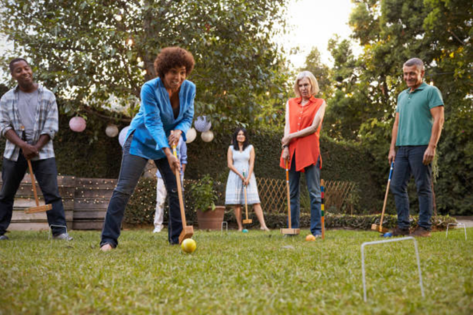 Older adults playing croquet outdoors at a hearing loss-friendly BBQ with outdoor games