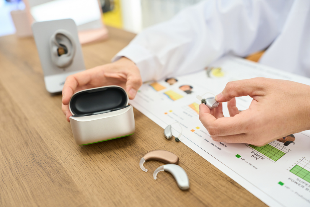 Hearing care professional comparing hearing aid models, one type of communication device for hearing loss